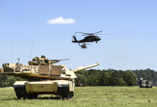 Un elicopter UH-60 Black Hawk și unul AH-64 Apache, zburând deasupra unui tanc american Abrams M1A2. Foto: Departamentul Apărării din SUA